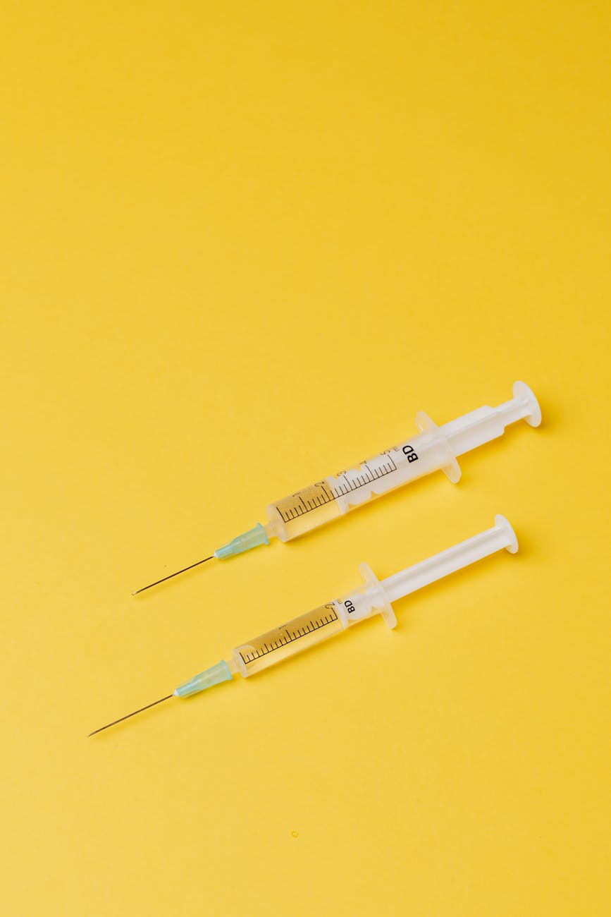 syringes with medical drugs on yellow background